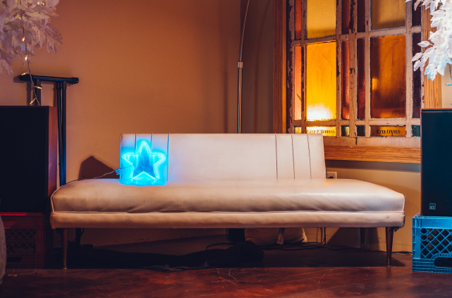 Listening area featuring a white couch with bright blue LED star, flanked by two floor speakers.