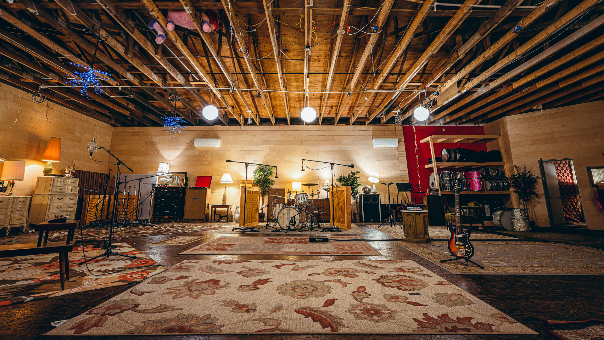 Showcase image of the live room, featuring guitars, drums and kits, and other equipment.