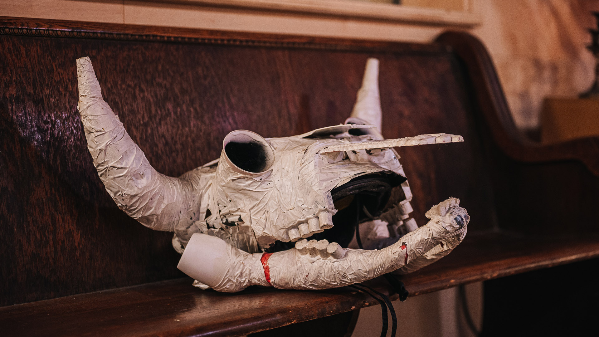 Paper mache bull skull sitting on a pew.